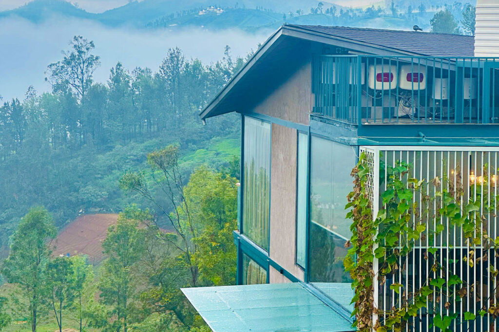 Morning view of Ooty Homz luxury homestay property surrounded by misty tea estates, capturing the serene beauty and calm ambiance of the hillside retreat
